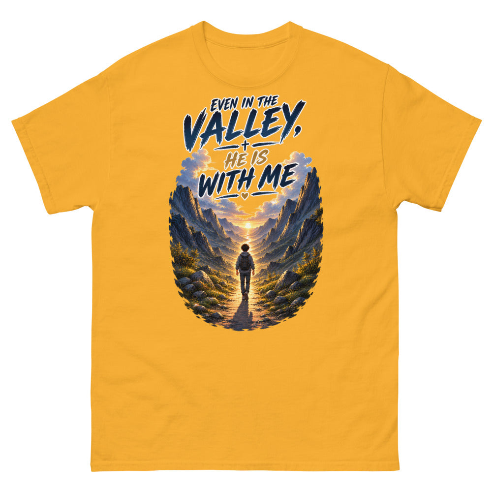 Hiker walking through a mountain valley with the words Even In The Valley He Is With Me on a Gold shirt