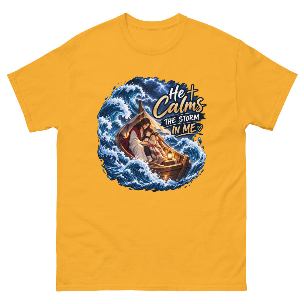 Jesus holding a young woman in a boat during a storm with the words He Calms The Storm In Me on a Gold shirt
