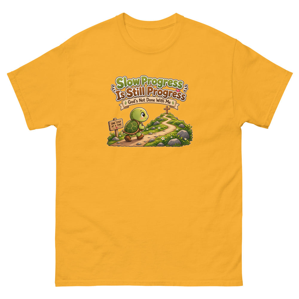 Cartoon turtle walking a path toward a cross with the words Slow Progress Is Still Progress on a Gold shirt