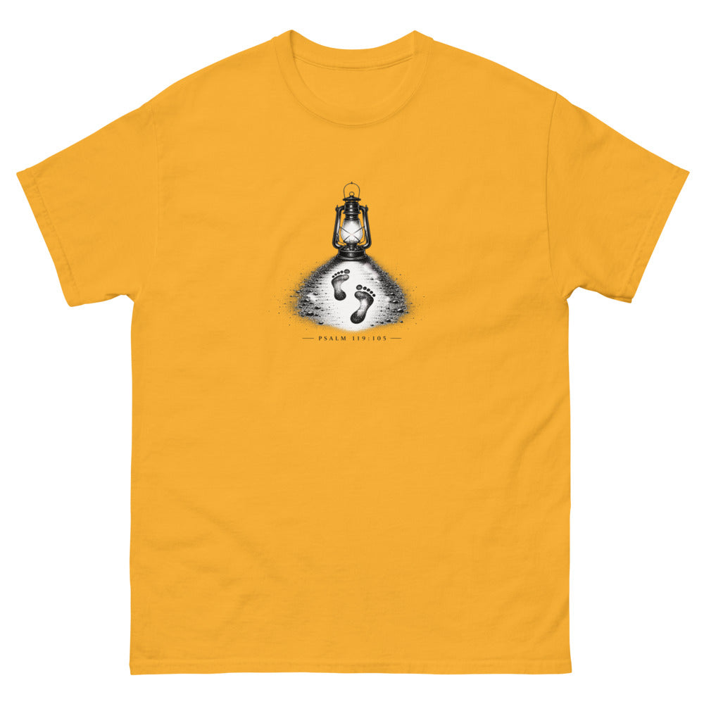 Stippled lantern lighting two footprints in sand with Psalm 119:105 on a Gold shirt