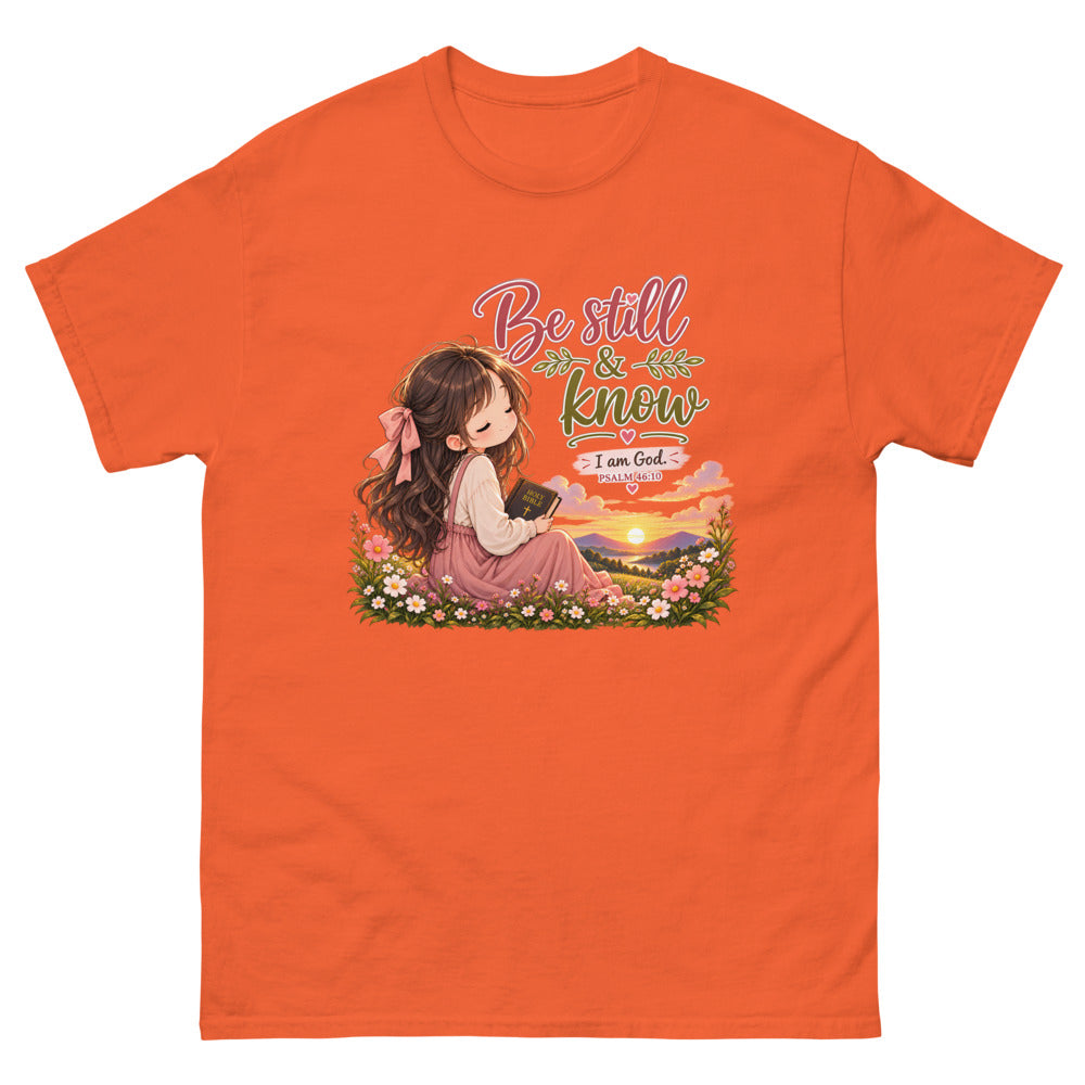 Chibi girl in a flower field holding a Bible with the words Be Still And Know on a Orange shirt
