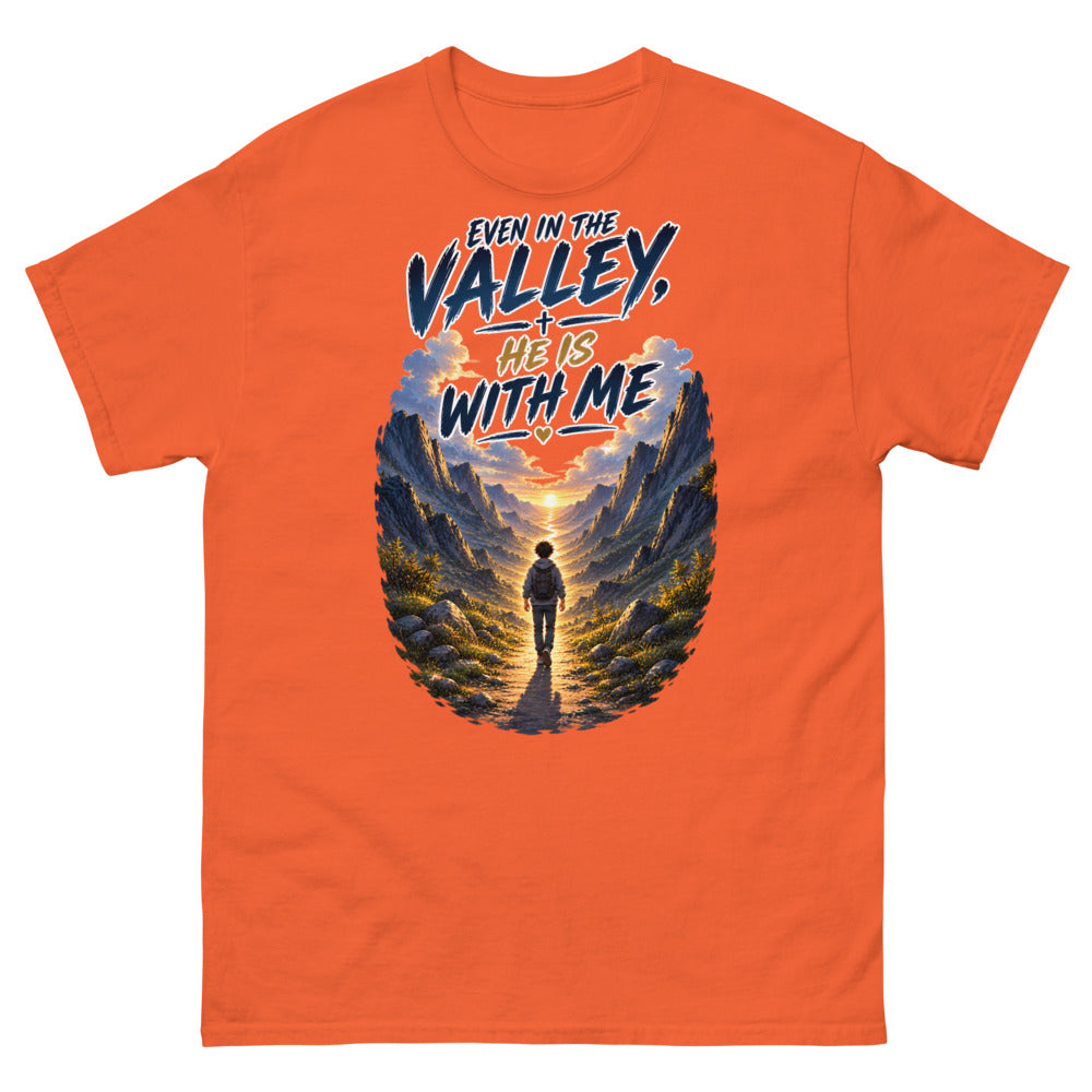 Hiker walking through a mountain valley with the words Even In The Valley He Is With Me on a Orange shirt