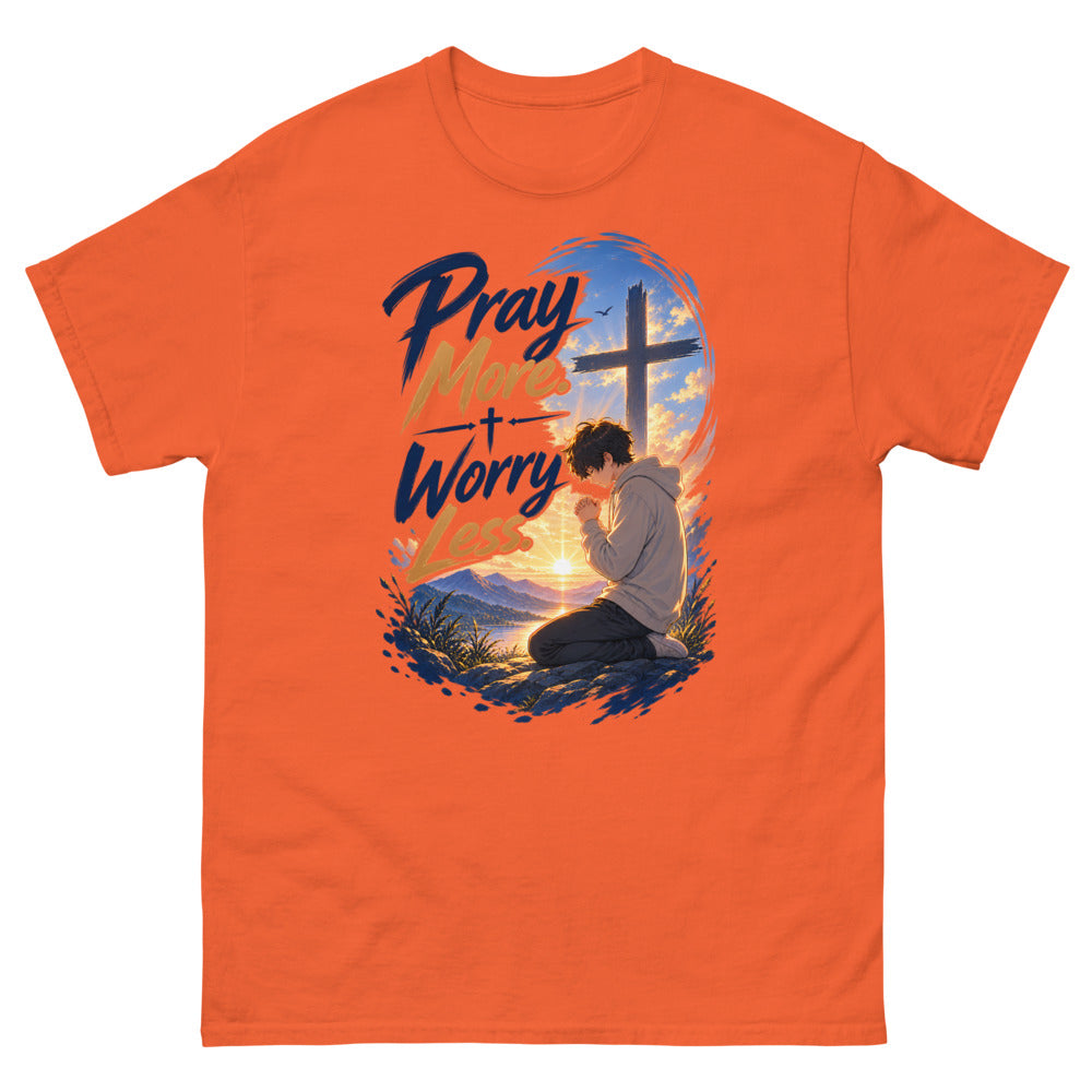 Anime boy kneeling in prayer at sunrise beneath a cross with the words Pray More Worry Less on a Orange shirt