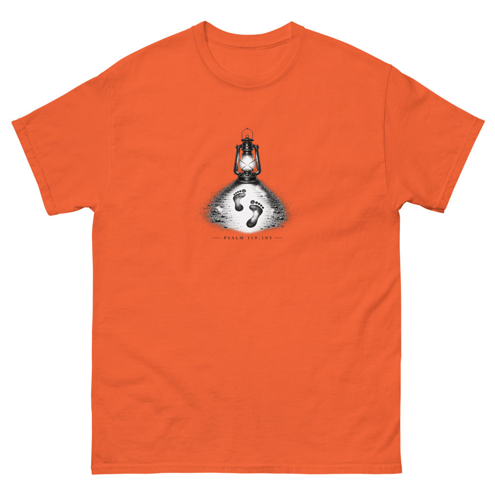 Stippled lantern lighting two footprints in sand with Psalm 119:105 on a Orange shirt