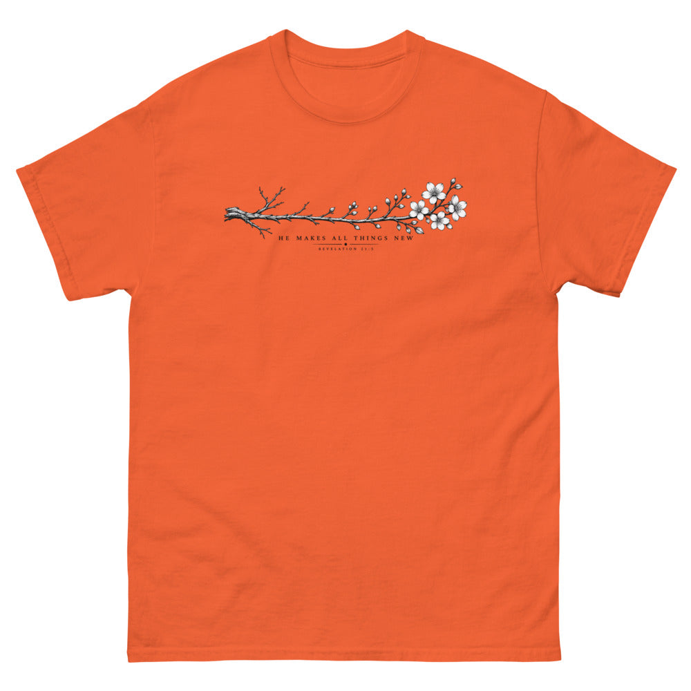 Line art branch flowering from bare to bloom with the words He Makes All Things New on a Orange shirt