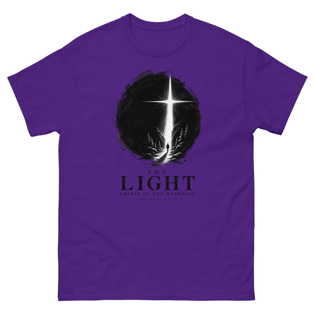 Ink circle with a figure walking toward a blazing cross reading The Light Shines In The Darkness on a Purple shirt