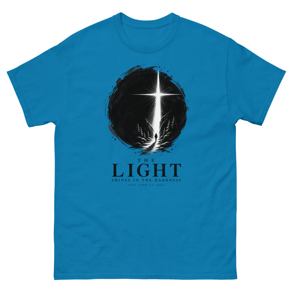 Ink circle with a figure walking toward a blazing cross reading The Light Shines In The Darkness on a Sapphire shirt